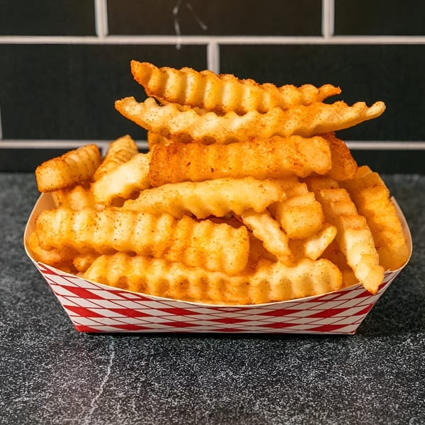 A red and white paper tray filled with crinkle-cut fries seasoned with spices, against a dark background.